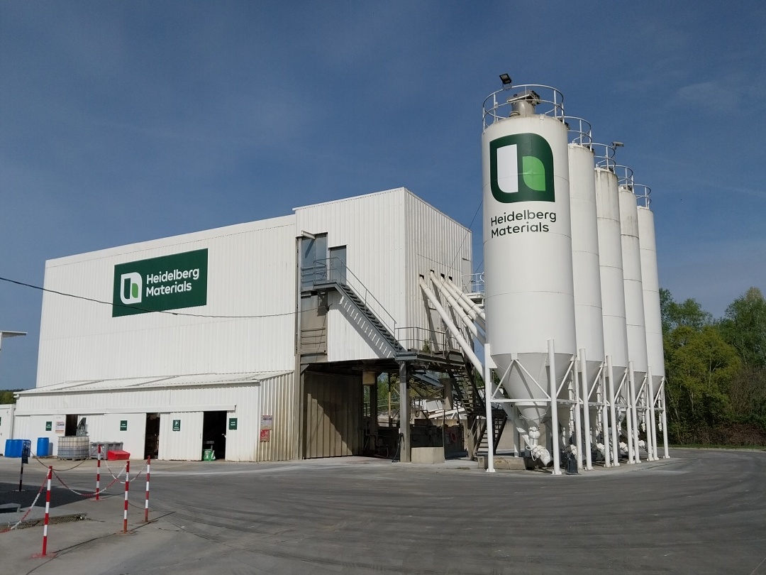 Bâtiment industriel de Heidelberg Materials avec des silos de stockage sur le site.