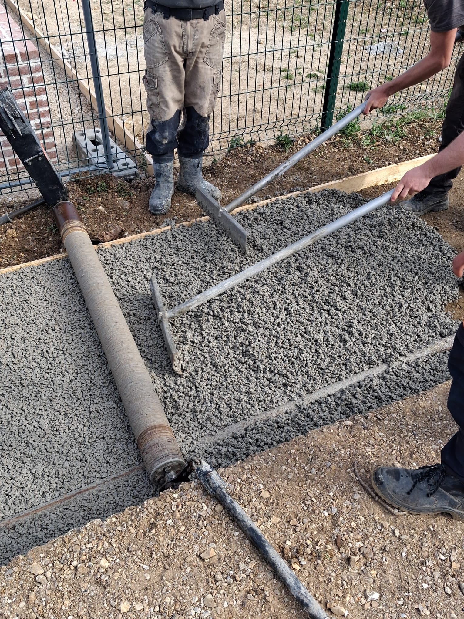Travailleurs nivelant du béton frais sur un chantier de construction.