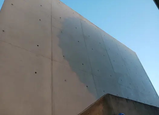Mur en béton avec une partie légèrement ombrée, sous un ciel dégagé.