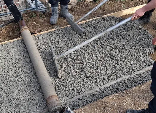 Travailleurs nivelant du béton frais sur un chantier de construction.