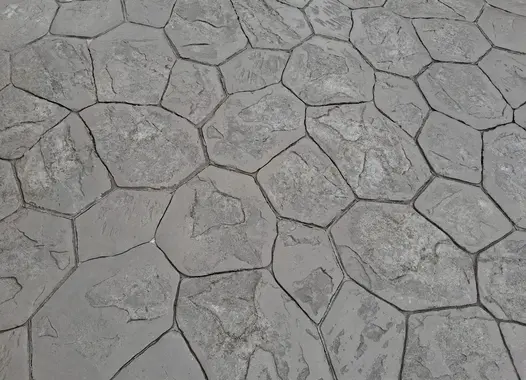 Sol en béton imprimé avec un motif de pierres hexagonales irrégulières.